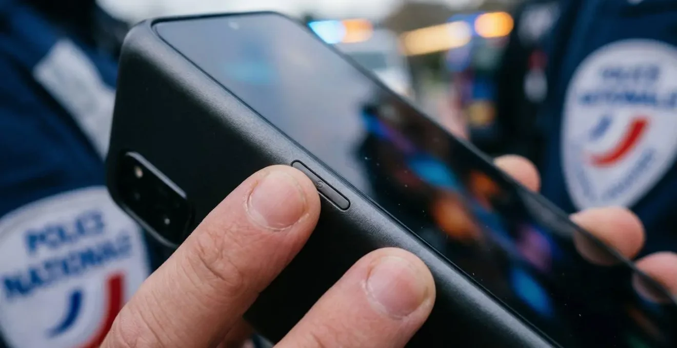 Main tenant un smartphone avec un document d'assurance en arrière-plan flou.